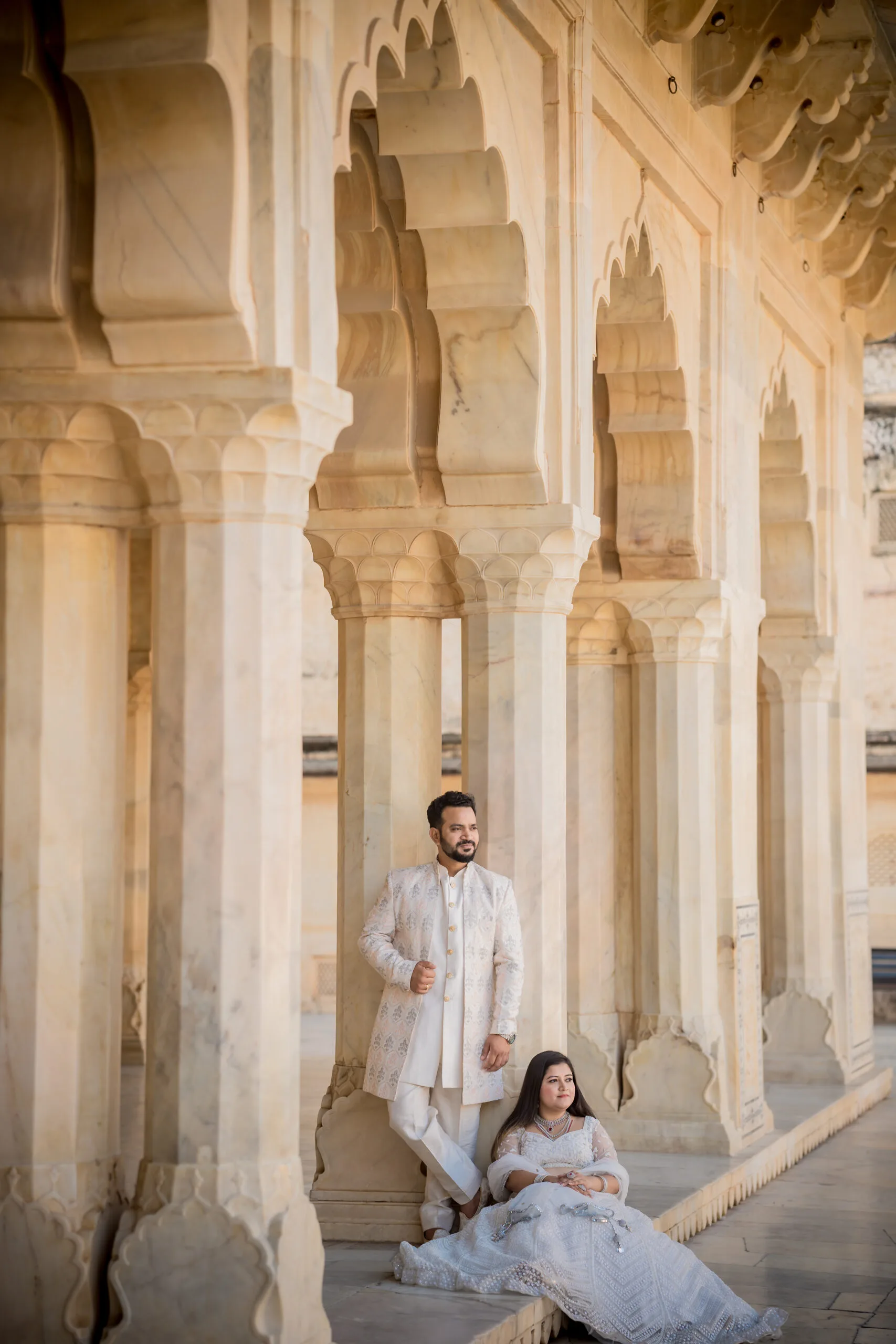 A couple in white outfits posing by the lake with Jal Mahal in the background for their Pre Wedding Shoot in jaipur.